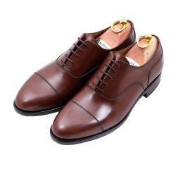 Model Oxford Cap Toe z zamkniętą przyszwą zapewnia formalny wygląd, doskonale komponując się z garniturem oraz strojem biznesowym.