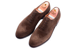 Eleganckie zamszowe obuwie z ażurkami i dekoracyjnymi zdobieniami koloru brązowego typu brogues z gumową podeszwą. Szyte metodą ramową.