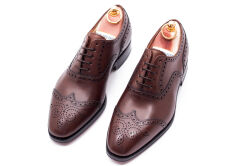 Eleganckie obuwie koloru ciemno brązowego typu brogues ze skórzaną podeszwą. Szyte metodą ramową.